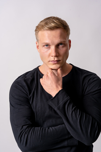 Attractive blond german model in a black sweater on a white background, posed in a pensive fashion