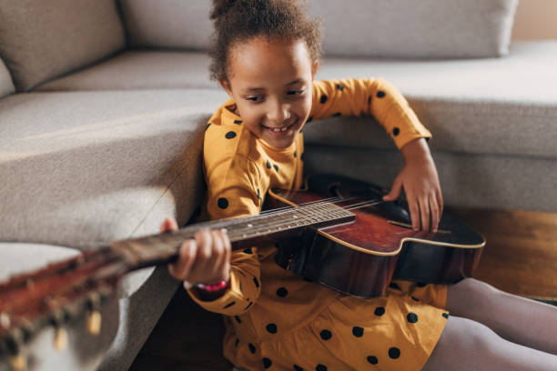 istock Little girl practicing playing a guitar at home 1442467303