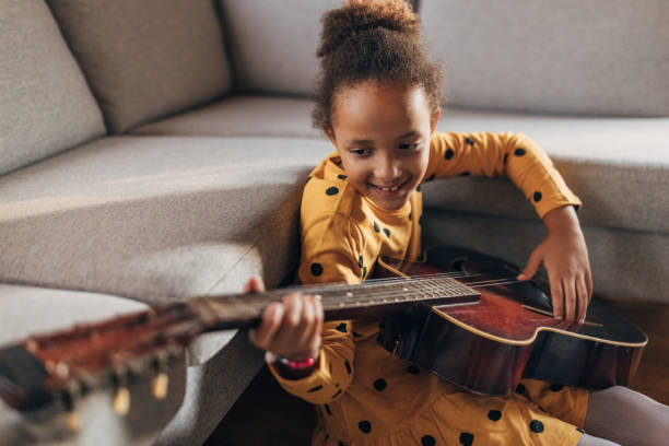 istock Little girl practicing playing a guitar at home 1442468328