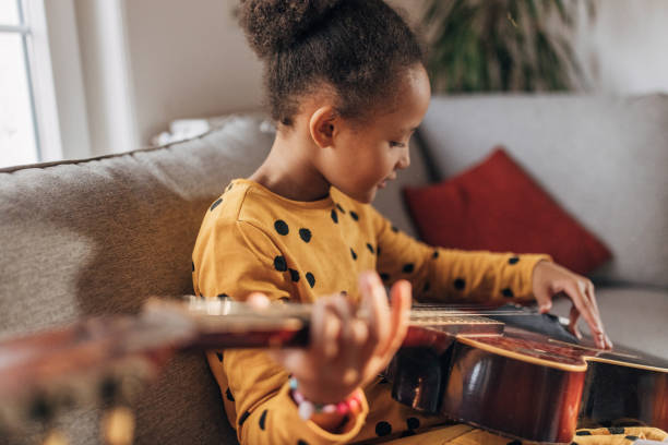istock Little girl practicing playing a guitar at home 1442468755
