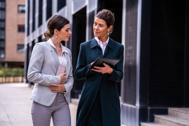 Mature and wealthy senior business woman with a middle-aged daughter having a calm conversation in a premium city outdoor locations about family business stock photo