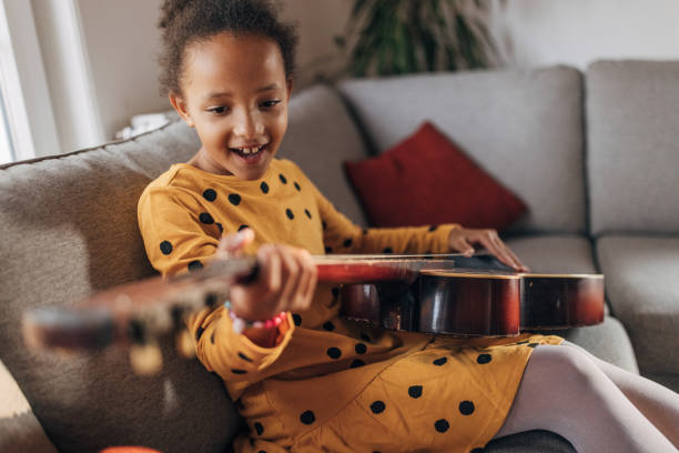 istock Little girl practicing playing a guitar at home 1442468795