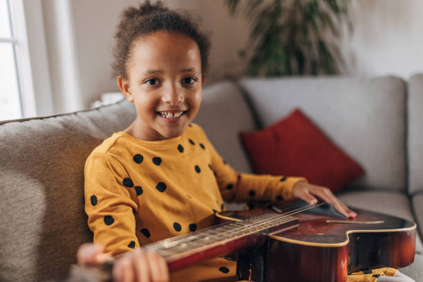 istock Little girl practicing playing a guitar at home 1442468839