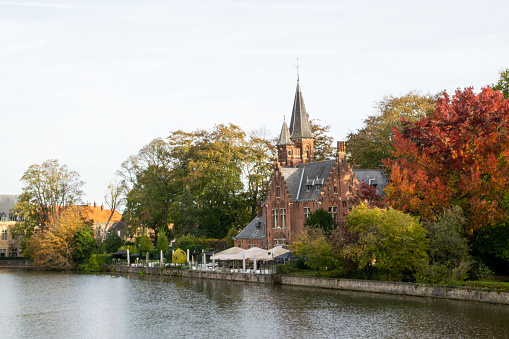 Minnewater Castle on the waterfront with the Minnewater Park in autumn colors in the city of Bruges, Belgium