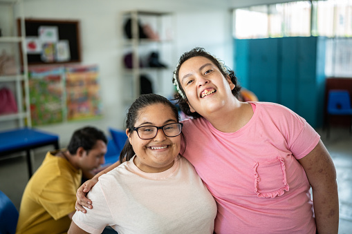 Portrait of disabled students embracing in the classroom at school