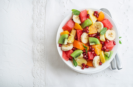 Bowl of healthy fresh tropical summer fruits on white background, top viewFresh salad bowl with tropical summer fruits