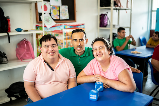 Portrait of mid adult teacher with their disabled students in the classroom at school