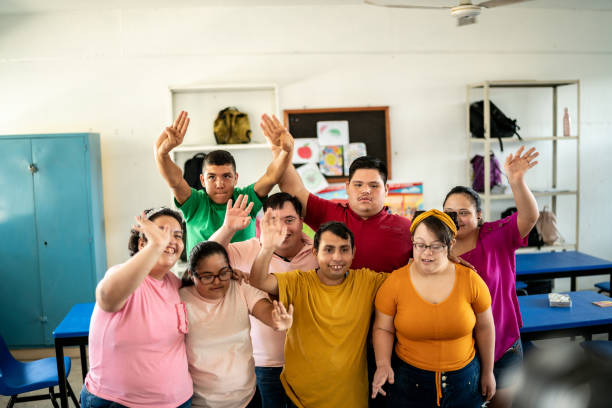 istock Portrait of disabled students waving in the classroom at school 1442476449