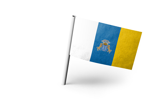 Small paper flag of Canary Islands pinned. Isolated on white background. Horizontal orientation. Close up photography. Copy space.
