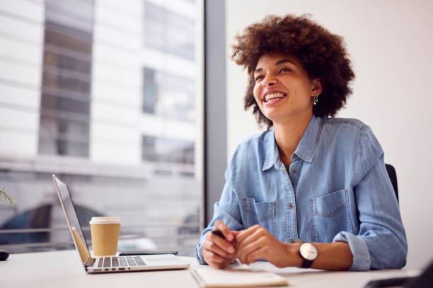 istock Young Businesswoman In Modern Office Working On Laptop Making Notes In Notebook 1442477139