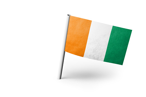 Small paper flag of Ivory Coast pinned. Isolated on white background. Horizontal orientation. Close up photography. Copy space.