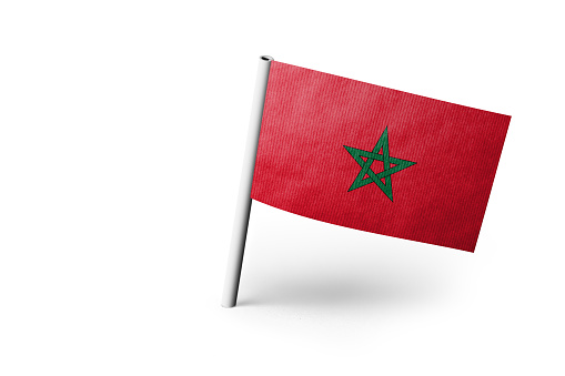Small paper flag of Morocco pinned. Isolated on white background. Horizontal orientation. Close up photography. Copy space.