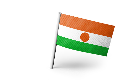 Small paper flag of Niger pinned. Isolated on white background. Horizontal orientation. Close up photography. Copy space.