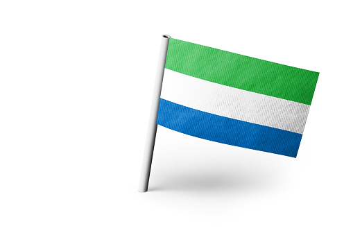 Small paper flag of Sierra Leone pinned. Isolated on white background. Horizontal orientation. Close up photography. Copy space.