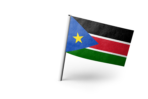 Small paper flag of South Sudan pinned. Isolated on white background. Horizontal orientation. Close up photography. Copy space.