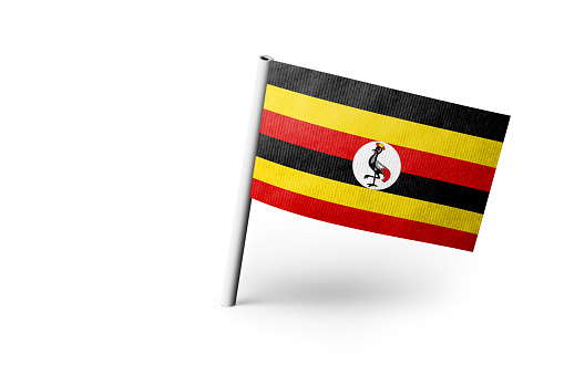Small paper flag of Uganda pinned. Isolated on white background. Horizontal orientation. Close up photography. Copy space.