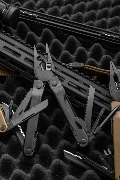 istock Modern multitool with many tools. A portable multi-tasking military tool lies next to the weapon. Dark background. 1442480815