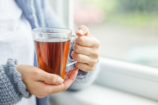 Cup of hot tea in female hands close-up. Background. Beverage concept, lifestyle, autumn and winter. Horizontal