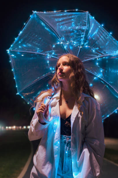 istock Young woman walking with umbrella with lights at night 1442482247