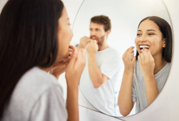 specchio, filo interdentale e denti sanitari di coppia che puliscono la bocca per gengive sane, sorriso e alito fresco. uomo e donna in bagno filo interdentale mattina durante la routine per l'igiene dentale al mattino - lifestyles toothy smile care beauty foto e immagini stock