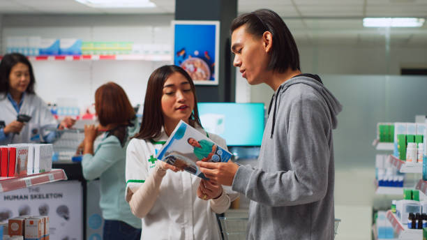 istock Pharmacist helping young man with healthcare leaflet 1442485725