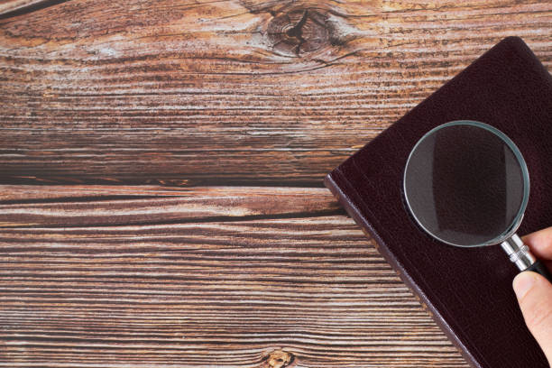 Holy Bible Book with a magnifying glass on rustic wooden background with copy space. Top table view. Christian concept of searching and studying the Scriptures.