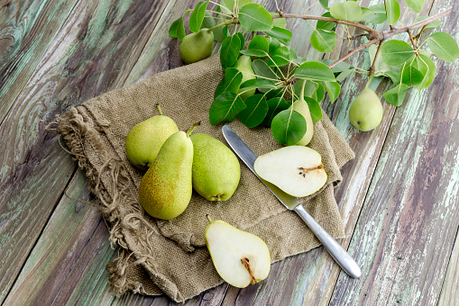 Fresh, ripe, green pears and knife on a wooden table close-up