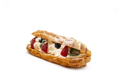 Traditional french dessert opened eclair with buttercream, fresh strawberries, icing sugar and mint on white.