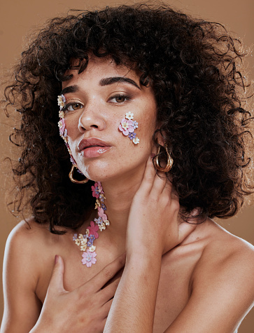 Makeup, model and flower eye makeup for beauty, wellness and skincare on face in studio portrait. Black woman, creative flowers and glow skin with cosmetics, health and floral pattern for body art