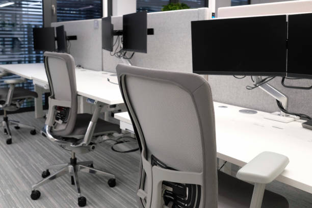 Empty desks in an office building Empty desks in an office building with several monitors hot desking stock pictures, royalty-free photos & images