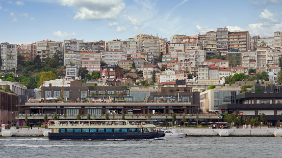 Istanbul, Turkey - September 1, 2022: Ferry boat sailing in Bosphorus Strait in front of Galataport, a mixed use development located in Karakoy neighbourhood