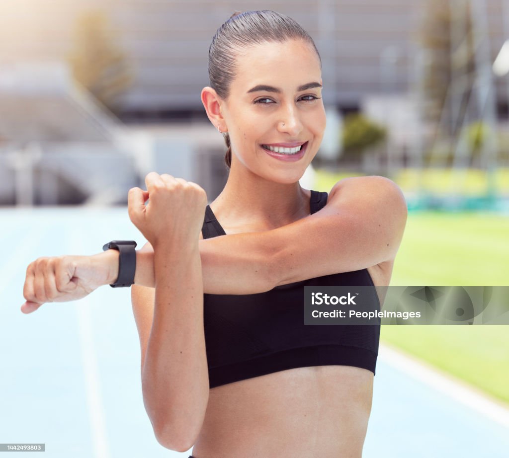 Fitness woman portrait, stretching arms and training on sports track for marathon, exercise and workout in stadium arena outdoor. Happy, smile and strong athlete prepare body to start cardio running Running Stock Photo