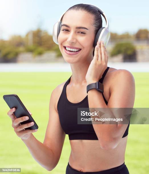 Headphones Fitness And Smartphone With Woman Listening To Motivation Podcast Or Music Outdoor On Sports Field With Portrait Athlete Girl With 5g Cellphone And Audio For Workout Training Or Exercise Stock Photo - Download Image Now