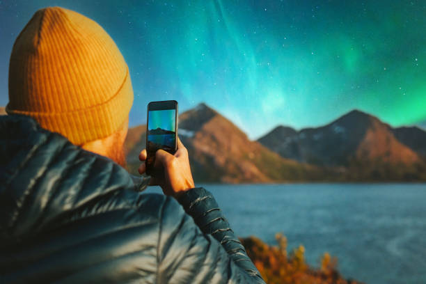 hombre con teléfono inteligente tomando foto de auroras boreales viajes de invierno en noruega vacaciones de aventura blogger al aire libre influencer estilo de vida tecnología moderna en línea - norte de noruega fotografías e imágenes de stock