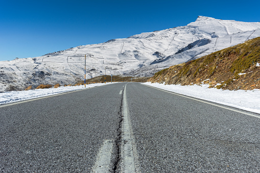 Empty road towards the snow-covered Sierra Nevada mountains. Granada, Spain,