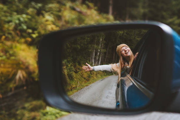 Road trip woman traveling by rental car adventure lifestyle vacation vibes outdoor forest view mirror reflection freedom concept stock photo