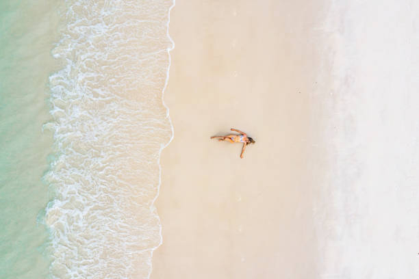 istock Woman sunbathing on white sand beach 1442497474