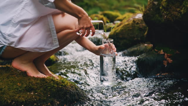 SLO MO Woman refills bottle with water from the stream