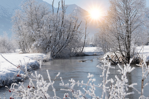 landscape in winter with mountain range and sun on blue sky