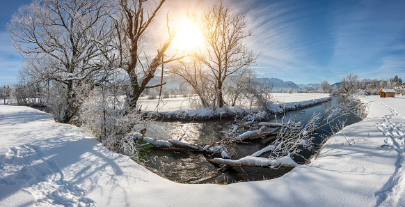 landscape in winter with mountain range and sun on blue sky