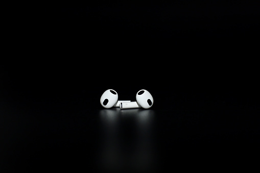 Kyiv, Ukraine - October 14, 2022: Apple AirPods (3rd generation). True wireless earphones, earbuds from Apple. White Apple AirPods 3 with Spatial Audio on black background
