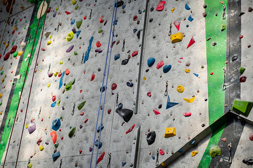 Close up photo of a rock climbing wall with climbing holds in gym.