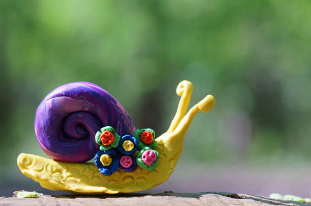 A toy snail decorated with a flower. A symbol of spring. Plasticine figurines.