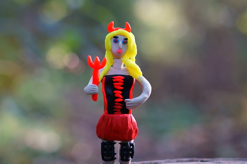 A figure of a toy devil in close-up. Female appearance. Smart suit.