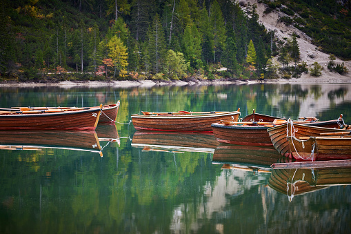 Wooden boats on the alpine Lake Braies, Lago di Braies or Pragser wildsee, Italy. Dolomites, South Tyrol. You can see the reflection of the boats and the mountains in the water.