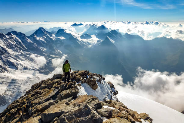 istock Enthusiastic mountaineer hiking on Jungfrau summit with  panoramic mountain view the background. Jungfrau-Höhenweg, Bernese Alps, Switzerland, Europe. 1442515686