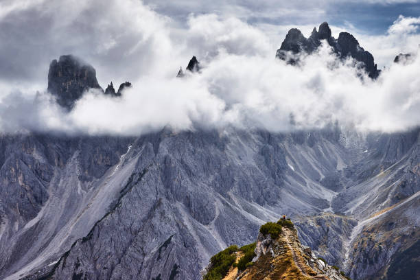 Man hiker standing and admiring stunning beauty of impressive jagged peaks of Cadini di Misurina mountain group in Dolomites, Italy, part of Tre Cime di Levaredo national park.