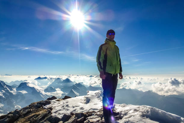 Hiker with yellow jacket on top of the mountain looking at the sea of clouds in the clean blue sky