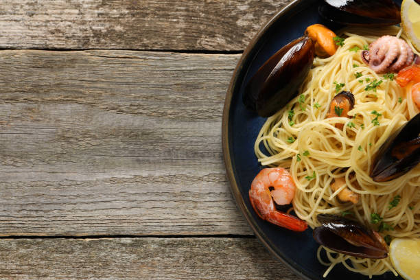 istock Delicious spaghetti with seafood served on wooden table, top view. Space for text 1442515921