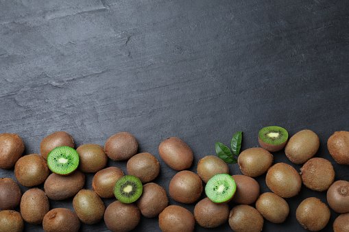 Fresh ripe kiwis on black table, flat lay. Space for text